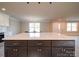 Close-up of a large kitchen island with seating, granite countertop, and view to entry of the house at 1133 Heather Oak Ln, Oakboro, NC 28129