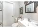 Small bathroom features decorative mirror, white basin sink, artwork and a white door at 1007 Ashford St, Charlotte, NC 28214