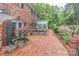Brick patio adjacent to greenhouse, framed by lush landscaping, flowering plants, and mature trees at 715 Saint Cloud Dr, Statesville, NC 28625