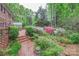 Brick patio with garden view features greenhouse, mature trees, brick path, and variety of blooming azaleas at 715 Saint Cloud Dr, Statesville, NC 28625