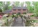 Charming two-story brick home with greenhouse feature, surrounded by lush landscaping and a wooden bridge entrance at 715 Saint Cloud Dr, Statesville, NC 28625