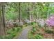 Lush garden with a winding stone path amid flowering azaleas, mature trees, and manicured shrubs at 715 Saint Cloud Dr, Statesville, NC 28625