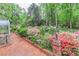 Brick patio with an open greenhouse adjacent to landscaped gardens featuring flowering azaleas and lush greenery at 715 Saint Cloud Dr, Statesville, NC 28625