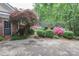 Home with lush side yard, blooming bushes, mature trees, brick accents and concrete patio at 715 Saint Cloud Dr, Statesville, NC 28625