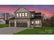 Dusk view of a large two-story home features a three-car garage and stone accents at 171 Heartland Dr # 7, Rock Hill, SC 29732