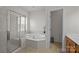 Modern bathroom featuring a soaking tub, glass-enclosed shower, and tiled flooring at 9341 Lenox Pointe Dr, Charlotte, NC 28273