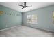 Bedroom features a ceiling fan, carpet flooring, and a charming solar system accent wall at 9341 Lenox Pointe Dr, Charlotte, NC 28273