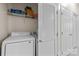 Laundry room with a white front load washer and dryer, white door, and storage shelf at 9341 Lenox Pointe Dr, Charlotte, NC 28273