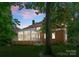 A brick home features a screened porch, overlooking a spacious backyard with mature trees at twilight at 4301 Fairview Oaks Dr, Charlotte, NC 28211