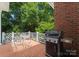 Cozy backyard patio with a brick floor, grill, wrought iron table set, and lush greenery at 4301 Fairview Oaks Dr, Charlotte, NC 28211
