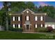 Elegant brick home with symmetrical design, black shutters, and meticulously landscaped front yard at 4301 Fairview Oaks Dr, Charlotte, NC 28211