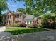 Stately brick home featuring a well-manicured lawn, mature landscaping, and a circular driveway at 4301 Fairview Oaks Dr, Charlotte, NC 28211
