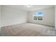 A well-lit bedroom boasts plush carpeting, a neutral palette, and a window with picturesque views of the outdoors at 8736 Acadia Pkwy # 601, Sherrills Ford, NC 28673
