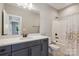 Modern bathroom featuring a vanity with gray cabinets, a large mirror, and a shower-tub combo at 16004 Deer River Rd, Charlotte, NC 28278