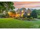 Brick home with manicured landscaping and nighttime lighting at 7025 Willow Trace Ln, Weddington, NC 28104