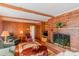 Cozy living room featuring a brick fireplace, wood paneling, and comfortable seating at 1405 Northcrest Dr, Albemarle, NC 28001