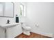 A white, cozy powder room features a single pedestal sink and wooden floors at 6178 Chimney Bluff Rd, Lancaster, SC 29720