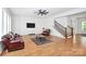 Well-lit living room featuring hardwood floors, a black ceiling fan, and staircase with black metal railings at 6178 Chimney Bluff Rd, Lancaster, SC 29720