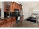 View of the kitchen featuring cherry wood cabinetry, black appliances, and a large sink at 720 Miller Chapel Rd, Salisbury, NC 28147