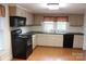 Eat-in kitchen with black appliances, light cabinets, laminate flooring, and double-basin sink at 436 E Oakwood Ave, Albemarle, NC 28001
