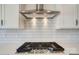 Close up of stainless steel range with overhead vent and tile backsplash in a modern kitchen at 2008 Embassy Ct # 45, Charlotte, NC 28213
