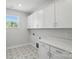 Bright laundry room featuring white cabinets, a countertop, and patterned tile flooring at 3253 Mcharney Dr # 27, Harrisburg, NC 28075