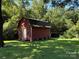 Outbuilding surrounded by lush greenery on a well-maintained lawn provides extra storage at 4549 Nc Highway 109 N Hwy, Troy, NC 27371