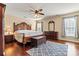 Spacious main bedroom features a dark wood bed frame, a fan, and hardwood floors at 7876 Rebecca Rd, Denver, NC 28037