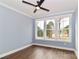 Light-filled bedroom featuring hardwood floors, a modern ceiling fan, and views from the three large windows at 332 Canvasback Rd, Mooresville, NC 28117