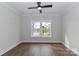 Neutral bedroom featuring wood-look flooring, a ceiling fan, and ample natural light through the window at 332 Canvasback Rd, Mooresville, NC 28117