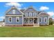 Charming two-story home featuring a covered front porch, brick accents, and a well-manicured lawn at 332 Canvasback Rd, Mooresville, NC 28117