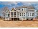 Rear exterior view featuring a large screened-in porch and a well-manicured lawn and landscape at 332 Canvasback Rd, Mooresville, NC 28117