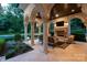 Covered patio with stone fireplace and outdoor furniture, adjacent to a well-manicured yard and pool at 423 Oakmont Ln, Waxhaw, NC 28173