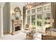 Sitting room with a stone fireplace, chandelier, and large windows overlooking lush greenery at 423 Oakmont Ln, Waxhaw, NC 28173