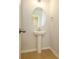 Simple bathroom with pedestal sink, circular mirror, and light fixtures at 10513 Boudreaux St, Huntersville, NC 28078