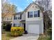 Charming two-story home with gray siding, black shutters, lush landscaping, and a convenient one-car garage at 1327 Phil Oneil Dr, Charlotte, NC 28215