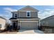 Two-story home featuring tan siding, stone accents, a two-car garage, and well-manicured landscaping at 158 Shepherds Landing Dr, Mooresville, NC 28115