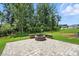 Backyard with a paver patio, a built-in fire pit, and a lush lawn surrounded by mature trees at 3229 Mcharney Dr # 30, Harrisburg, NC 28075