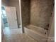 Tiled bathroom featuring a white tub and marble-like tiling with a window bringing in natural light at 3229 Mcharney Dr # 30, Harrisburg, NC 28075