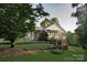 Side view of a charming home featuring a covered porch, brick accents, and mature trees offering shade at 3021 Davis Park Rd, Gastonia, NC 28052
