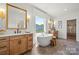 Bright bathroom featuring dual sinks, soaking tub, and a large window at 5216 Mint Harbor Way # 0284, Charlotte, NC 28269