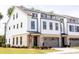 Modern three-story townhome with white siding, brick accents, black trim, and a rooftop deck at 3020 Endhaven Terraces Ln # 10, Charlotte, NC 28277