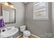 Small powder room with white pedestal sink and decorative mirror at 263 Fernbrook Dr, Mooresville, NC 28117