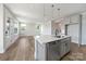 Bright, open kitchen with gray cabinets, stainless steel appliances, island with sink, and hardwood floors at 97 Seven Oaks Lndg, Belmont, NC 28012