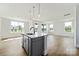 Bright, open kitchen with gray cabinets, stainless steel appliances, island with sink, and hardwood floors at 97 Seven Oaks Lndg, Belmont, NC 28012
