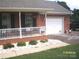 View of brick front porch, garage with white door and landscaping with plants at 3905 Autumn Wood Dr # 28, Monroe, NC 28112