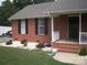 Close-up of a red brick house corner with black shutters and white rock landscaping. Scooter in yard at 3905 Autumn Wood Dr # 28, Monroe, NC 28112