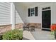 Inviting front porch featuring a sitting area with chairs, stone accents, and a black front door at 4028 Brandywine Ter, Lancaster, SC 29720