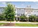 Three-story townhouses with gray and beige siding, landscaping, and a sidewalk at 9714 Ainslie Downs St, Charlotte, NC 28273