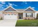 Charming single-story home with stone accents, gray siding, a well-manicured lawn, and an attached two-car garage at 180 Wembury Ln, Troutman, NC 28166